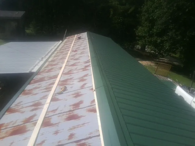 Old rusted panels beside newly installed green metal roofing — Wind Damage Roof Repair by Roofing Brothers in New Philadelphia